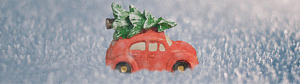 En röd bil i miniatyr med gran på taket står på en yta med frost