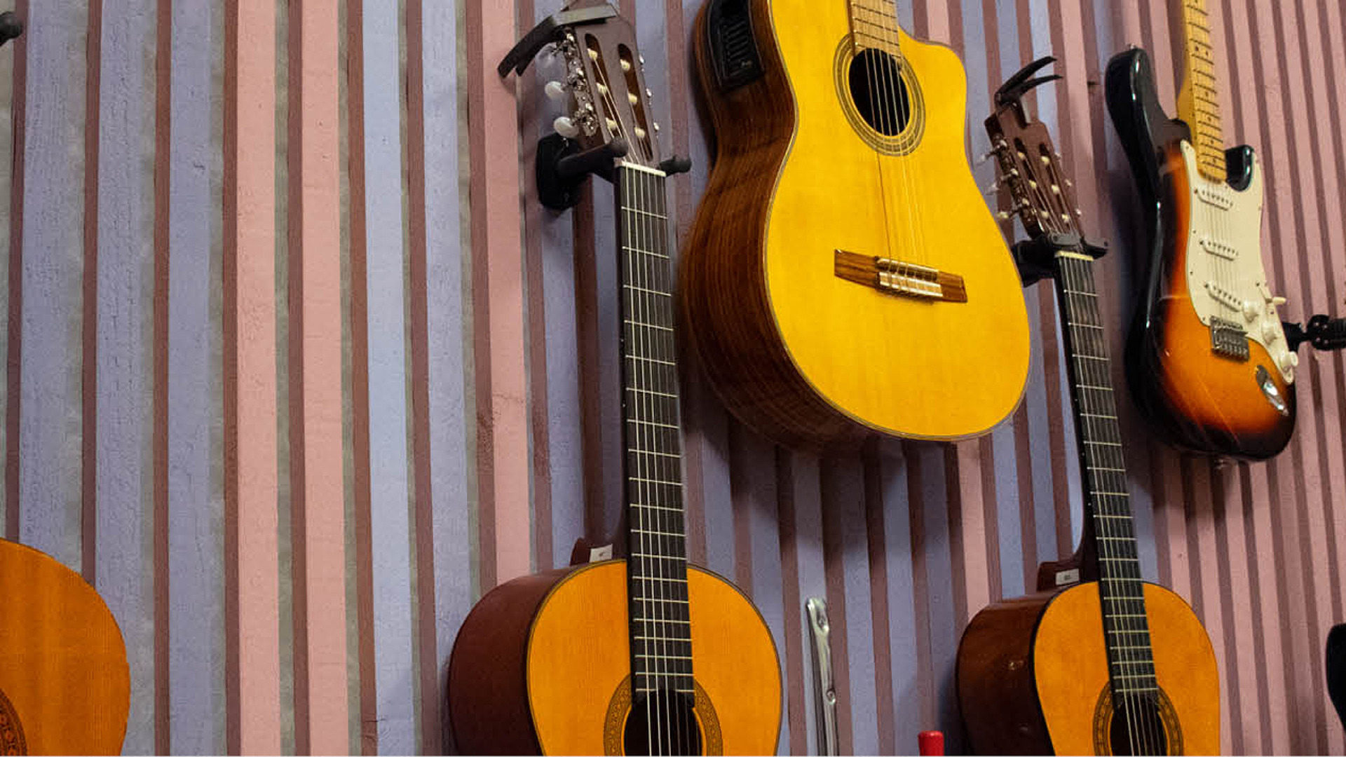 Gitarrer hänger på en vägg i lila och rosa färger
