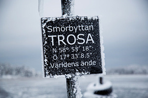 En vinterbild på skylt längst ut på piren i Trosa med texten 