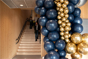 Marinblå och guldiga ballonger sammanknutna i förgrunden, en trappa i bakgrunden