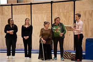 Fem kvinnor står intill varandra där en av dem pratar i mikrofon och en håller i en blombukett.