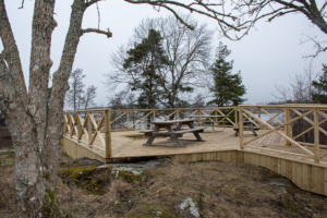 Trädäckad utsiktsplats med picknickbord.