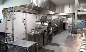 Skolkök där stora kokkärl i rostfritt stål står utmed väggarna
