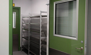 En öppen dörr till ett rum med hyllsystem i rostfritt stål