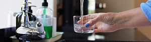 Ett glas fylls på med dricksvatten under en vattenkran.