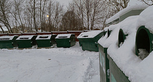 En återvinningsstation med containrar täckta av snö.