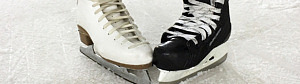 En vit och en svart skridsko placerade tå mot tå på isen.