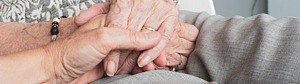 Närbild inomhus på ett äldre människor som håller hand.