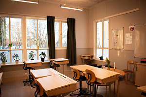 Klassrummet går i ljusa och jordnära färger. De nya bänkarna är i ljust trä och gardinerna är mörkt gröna.