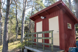 Två utedass i skogsmiljö.