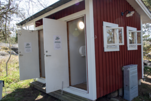 Två utedass med dörrarna öppna. Röda med vitmålade knutar.